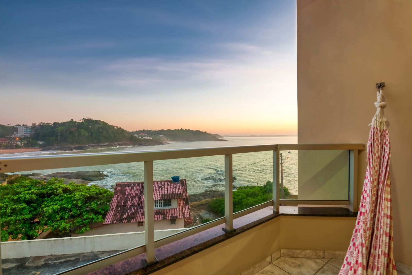 Varanda de quarto com rede e vista para a enseada ao amanhecer
